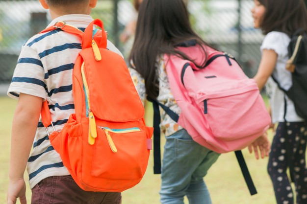 tres-alumnos-escuela-primaria-van-mano-muchacho-muchacha-bolsos-escuela-detras-parte-posterior-comienzo-clases-dia-calido-otono-vuelt