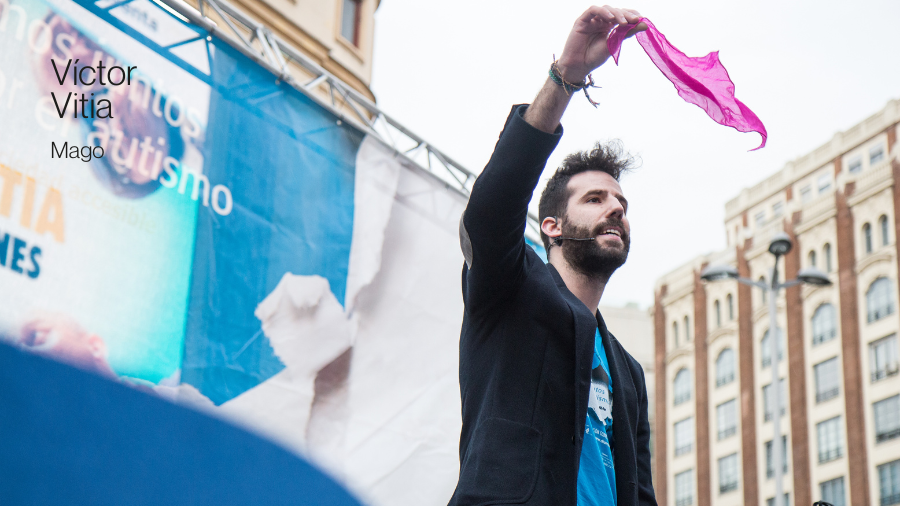 El mago Víctor Vitia cogiendo un pañuelo rosa sobre un escenario