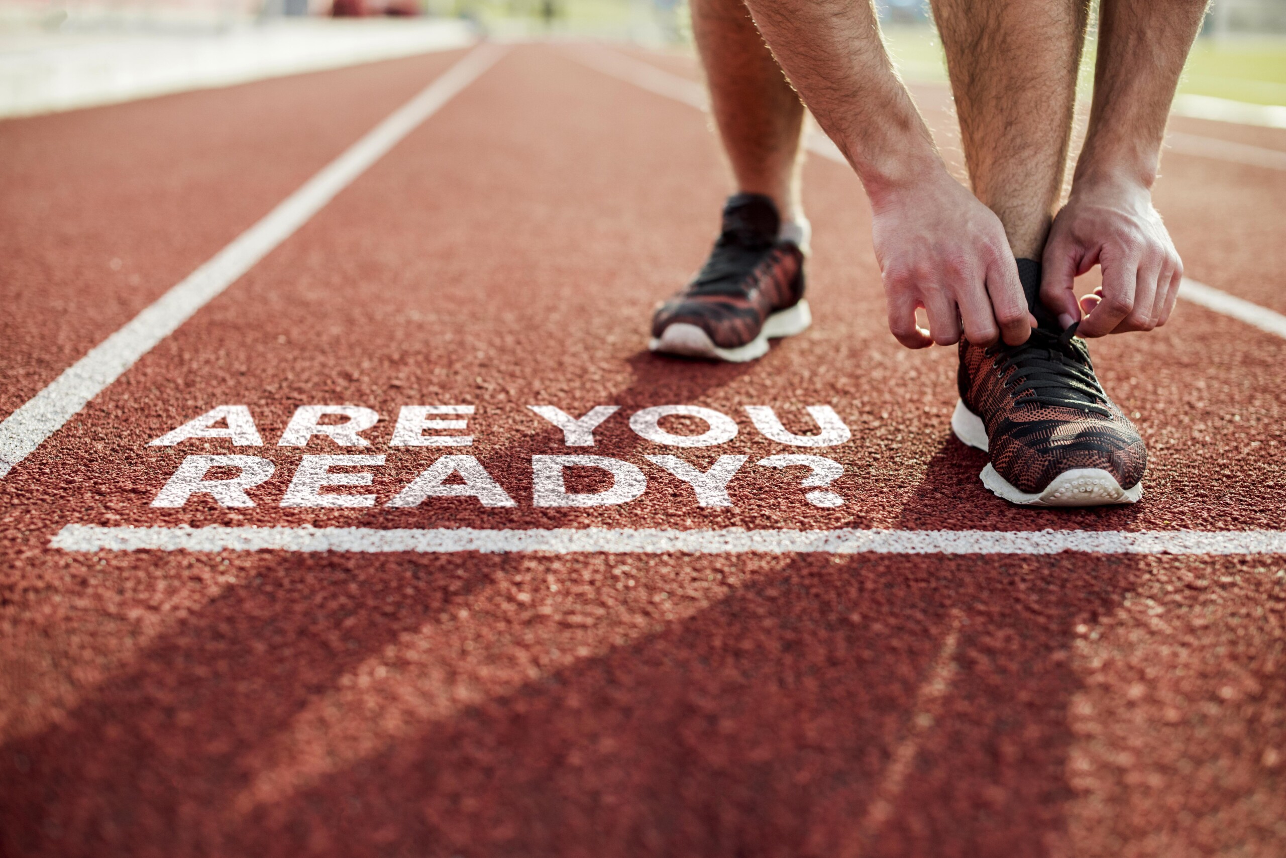 Unas manos atando unas deportivas en una pista de atletismo