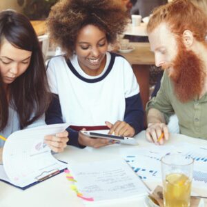 Tres personas jóvenes trabajan juntas en un proyecto.