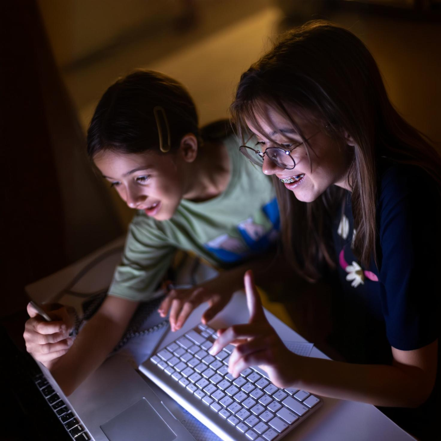 Chico y chica riéndose y trabajando en un ordenador.