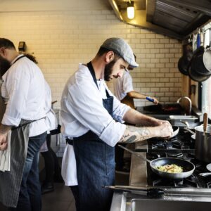 3 profesionales de la hostería trabajando en una cocina.