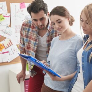 Tres personas adultas (profesionales) mirando un bloc de notas.