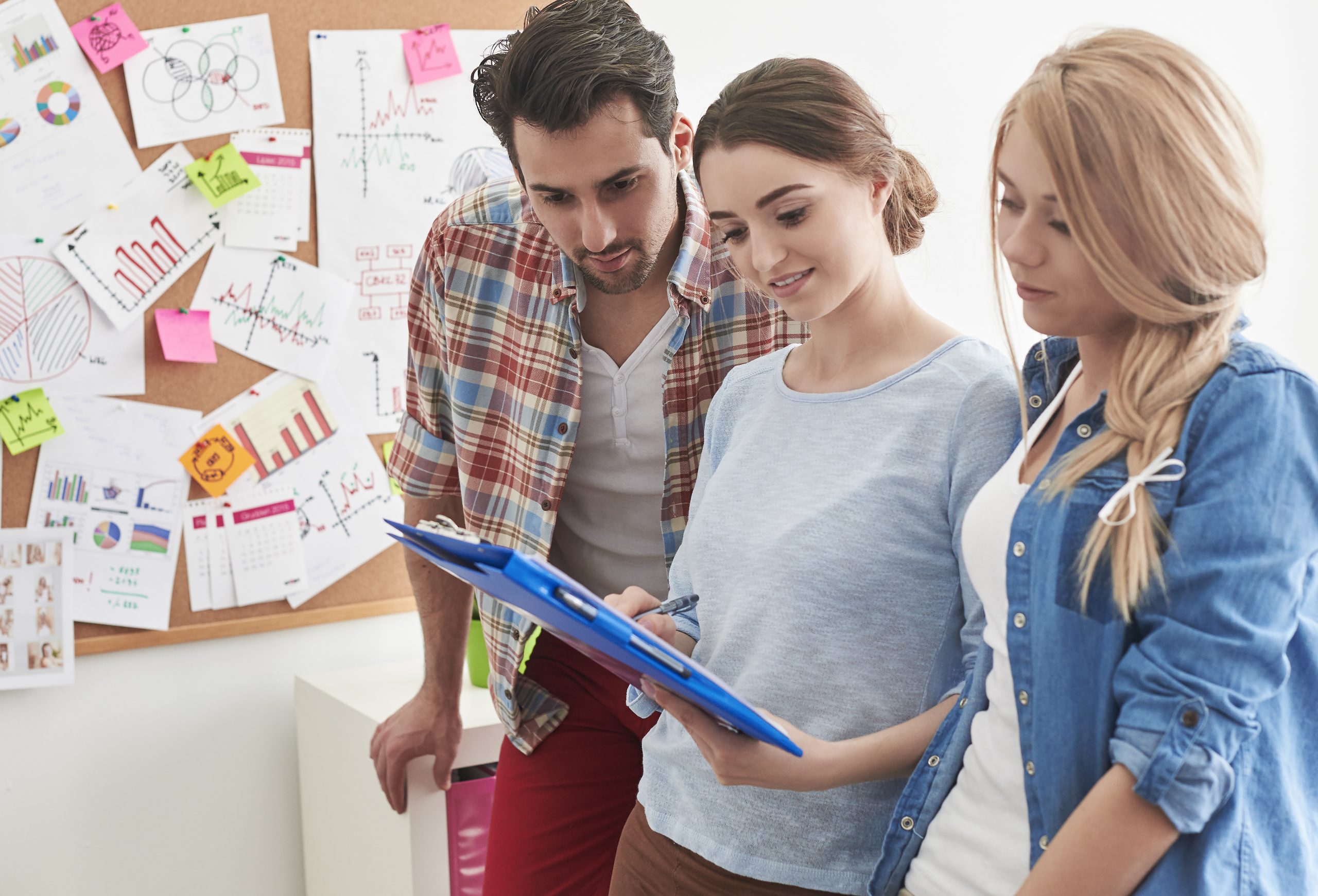 Tres personas adultas (profesionales) mirando un bloc de notas.