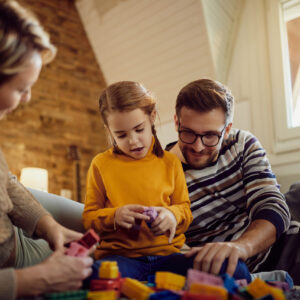 Padre y madre jugando con bloques con su hija.