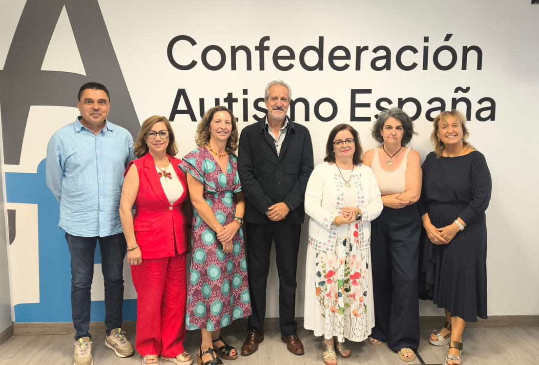 2 hombres y 5 mujeres posan delante de una pared con el logotipo de Autismo España